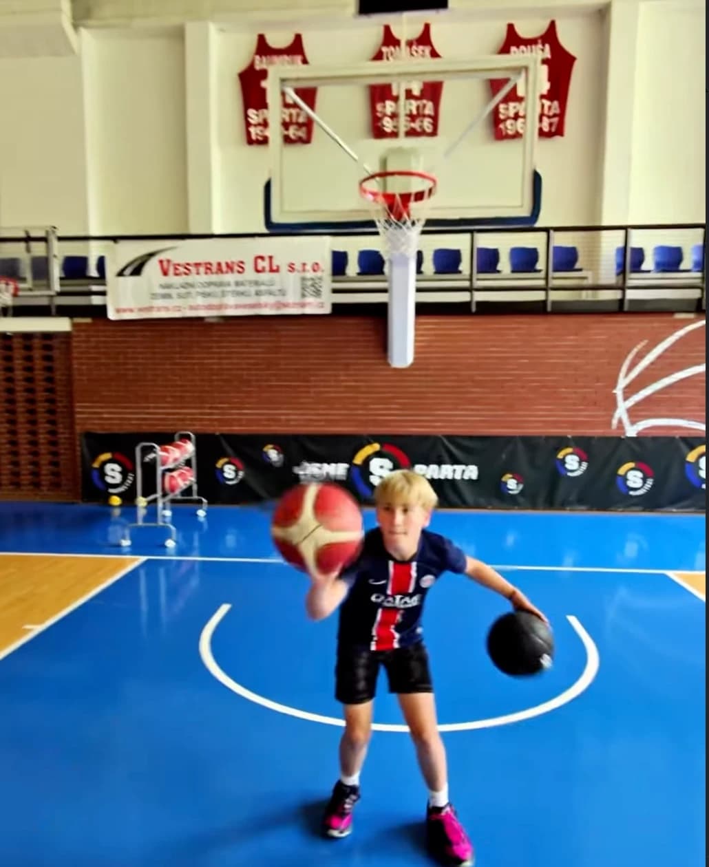Chlapec trénuje driblink se dvěma míči na hale Sparty
